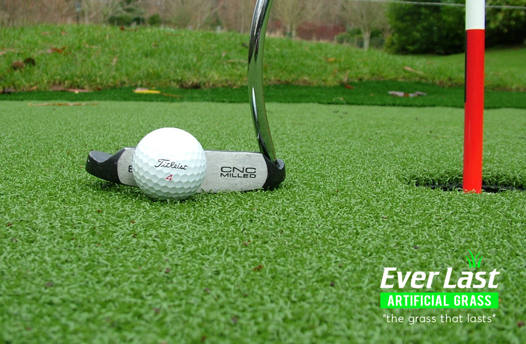 Artificial grass installed on golf green showing hole, golf putter and golf ball